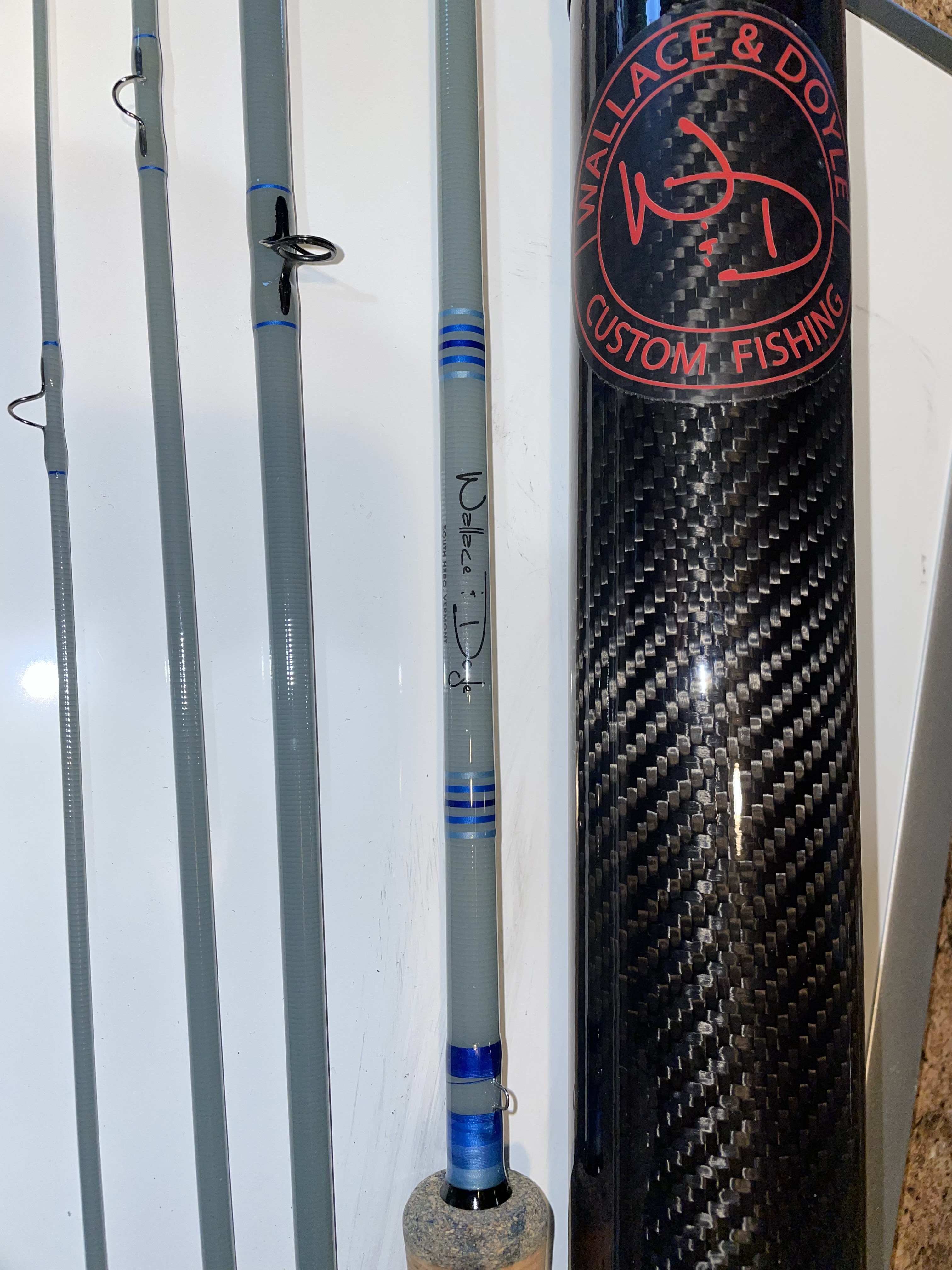 Wallace & Doyle rod sections beside a custom carbon fiber rod tube with the Wallace & Doyle Custom Fishing logo